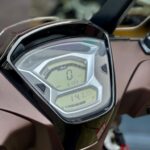 Close-up van het digitale dashboard van een scooter, met 0 km/u, 6199 km en brandstofmeter zichtbaar.