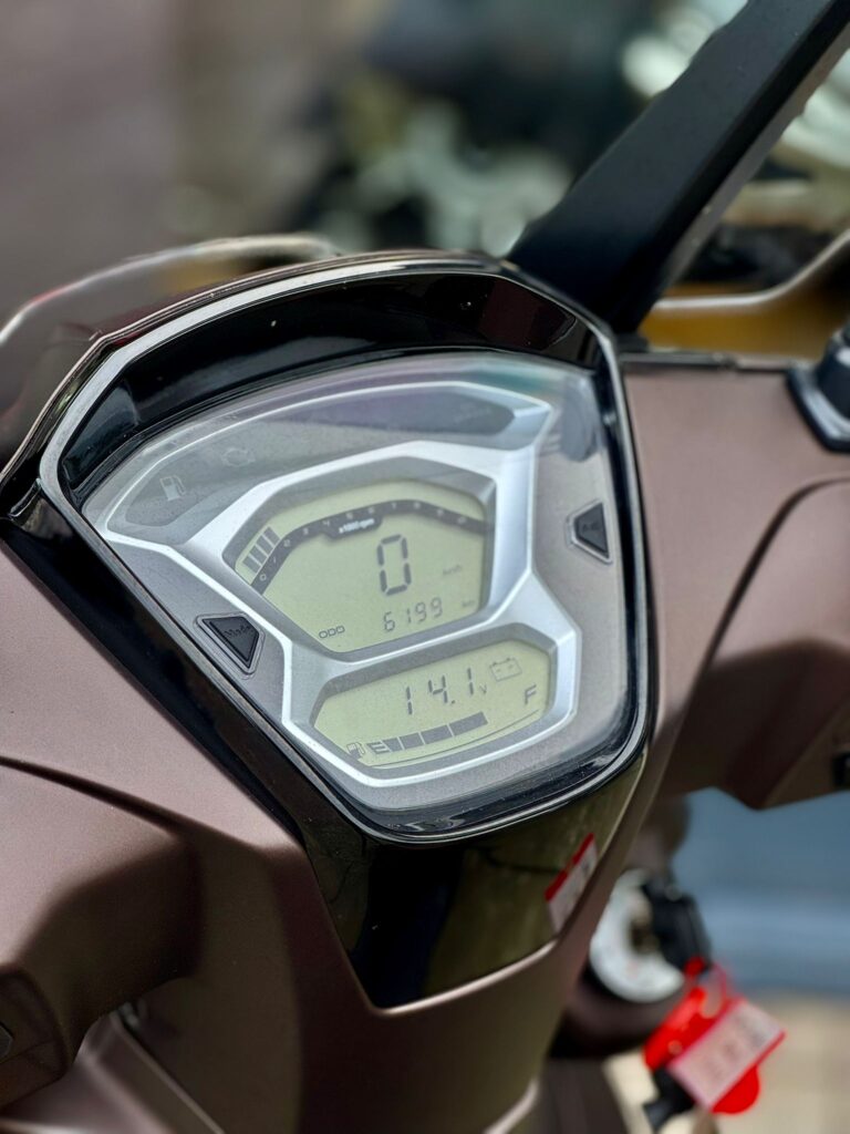 Close-up van het digitale dashboard van een scooter, met 0 km/u, 6199 km en brandstofmeter zichtbaar.