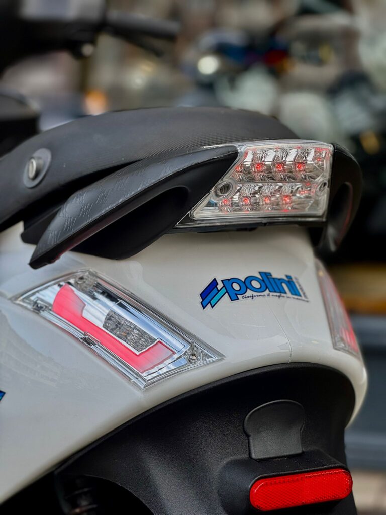 Close-up van de achterzijde van een witte scooter met LED-achterlicht en Polini-sticker.