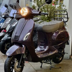 Paarse retro scooter met brandende koplamp op nat trottoir voor een winkel