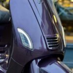 Close-up van de paarse voorkant van een scooter met LED-knipperlichten.