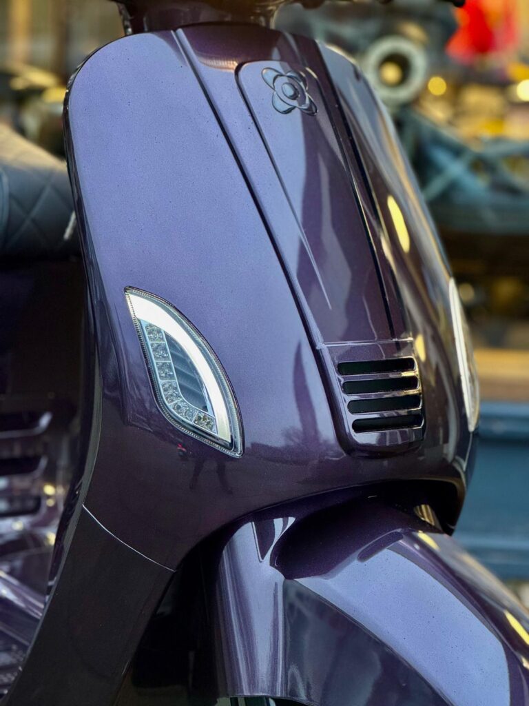 Close-up van de paarse voorkant van een scooter met LED-knipperlichten.
