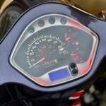 Close-up van het dashboard van een scooter met snelheidsmeter, brandstofmeter en digitale klok (8:45).