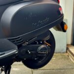 Close-up van de zijkant van een matte zwarte La Souris scooter met krassen op de kuip.