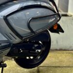 Close-up van de achterzijde van een grijze GTS Palermo scooter met valbeugel op stoeptegels.