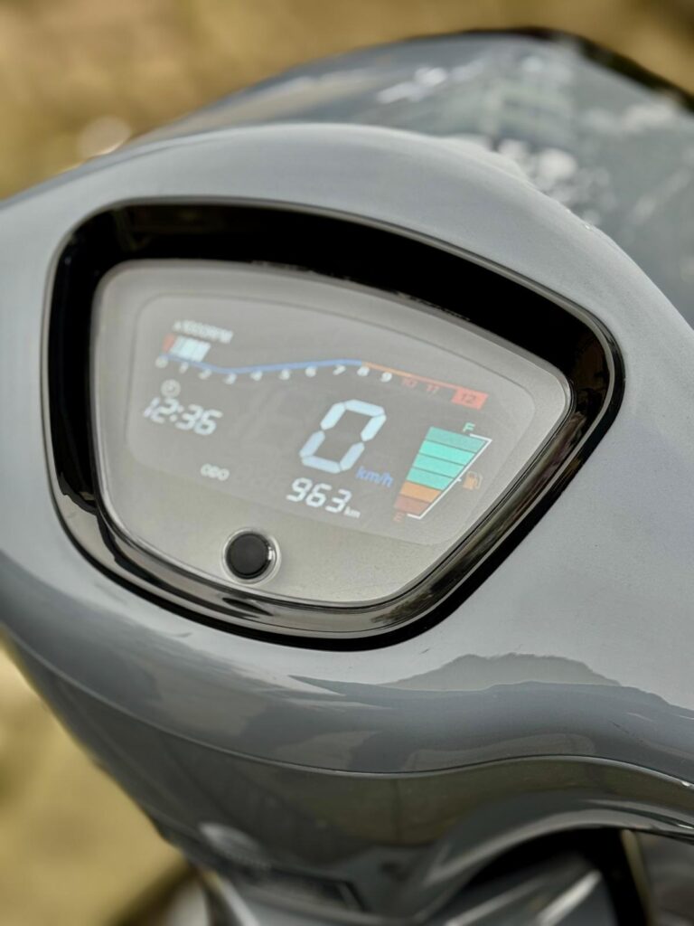 Close-up van digitaal scooterdashboard met 0 km/u, kloktijd 12:36 en 963 km op de teller.