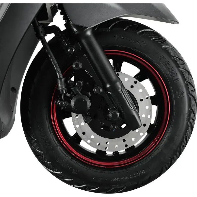 Close-up van een scooter voorwiel met schijfrem, zwarte band en rode velgrand.