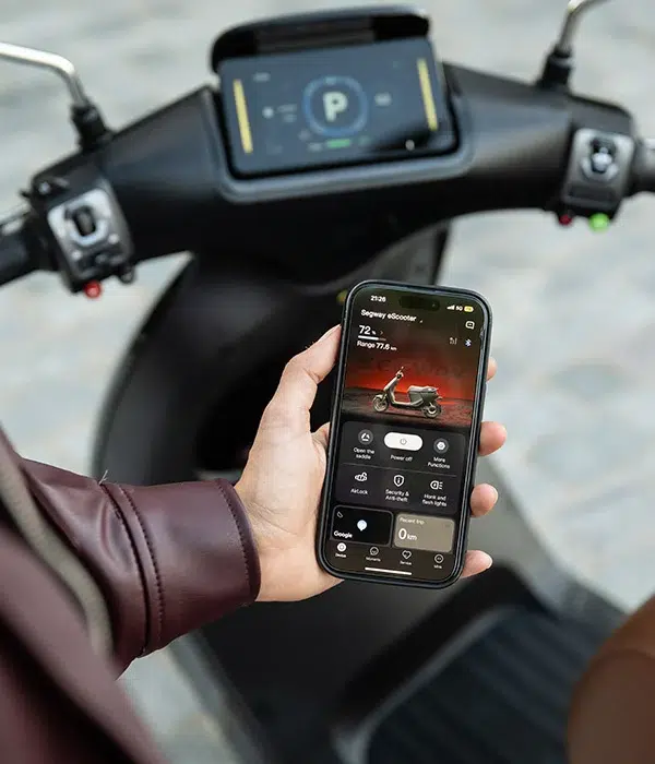 Hand met smartphone die een e-scooter app toont, voor het stuur en display van een scooter.