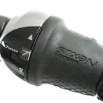 Detail van een fietsstuur met draaishifter voor 7 versnellingen en een lederen handgreep.