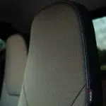 Close-up van een geperforeerde autostoelhoofdsteun met rode stiksels en Silence-label.