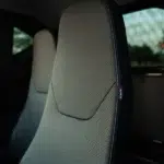 Close-up van een grijze geperforeerde autostoel met contrasterende stiksels.