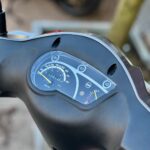Close-up van het dashboard van een scooter met snelheidsmeter en brandstofmeter.
