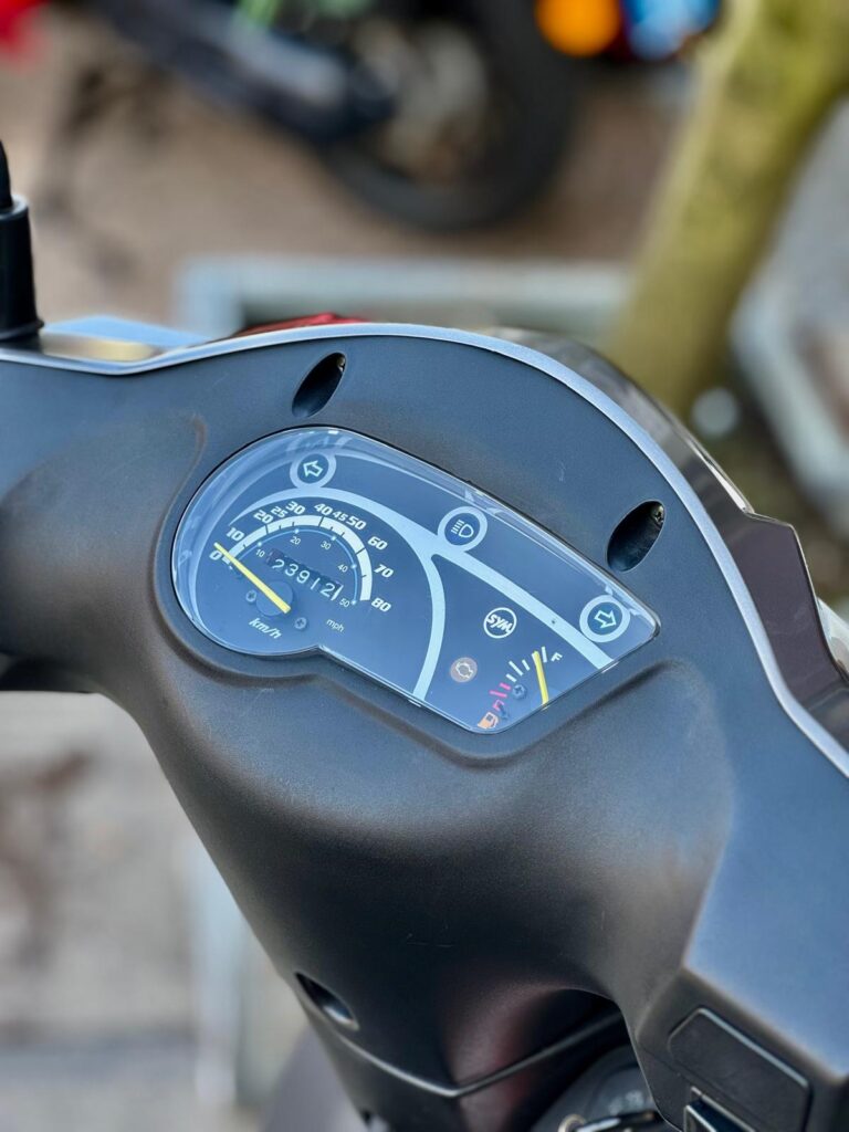 Close-up van het dashboard van een scooter met snelheidsmeter en brandstofmeter.