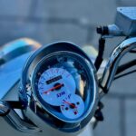 Close-up van het dashboard van een SYM-scooter met snelheidsmeter en brandstofmeter.