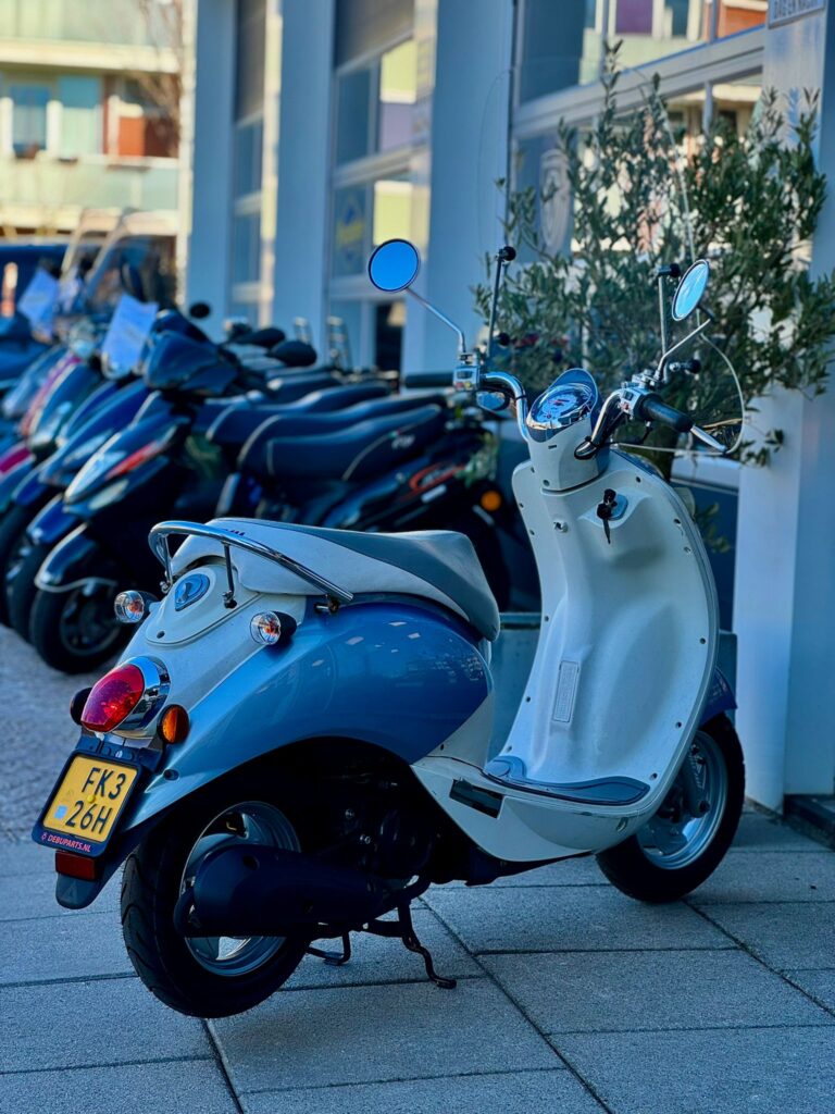 Lichtblauwe en witte retro scooter geparkeerd voor een rij scooters bij een showroom