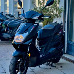 Zwarte scooter met sportieve lijnen geparkeerd voor een winkelpui, zijaanzicht.