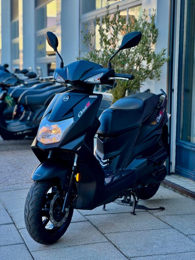 Zwarte scooter met sportieve lijnen geparkeerd voor een winkelpui, zijaanzicht.