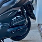 Close-up van de achterkant van een zwarte scooter, model Orbit III, met veer en achterwiel op stoeptegels.