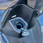 Close-up van een scooter met open brandstofdop aan de voorkant van de kuip.