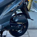 Detail van de achterzijde van een grijze Kymco Agility scooter met achterwiel en vering.
