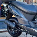 Close-up van de achterkant van een grijze Kymco Agility-scooter op de middenbok met topkoffer.