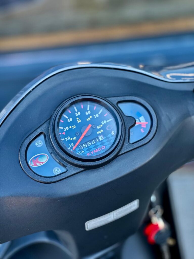 Close-up van het dashboard van een Kymco scooter met snelheidsmeter en brandstofmeter.