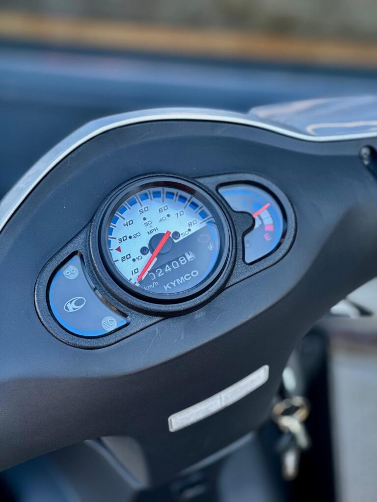 Close-up van het dashboard van een Kymco-scooter met snelheidsmeter en brandstofmeter.