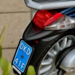 Close-up van het achterlicht, wiel en blauwe kentekenplaat van een scooter.