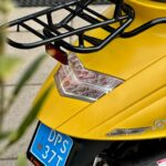 Gele scooter van achteren met bagagedrager, achterlicht en blauwe kentekenplaat