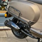 Close-up van de achterkant van een matte bronzen La Souris scooter met uitlaat en bagagerek.