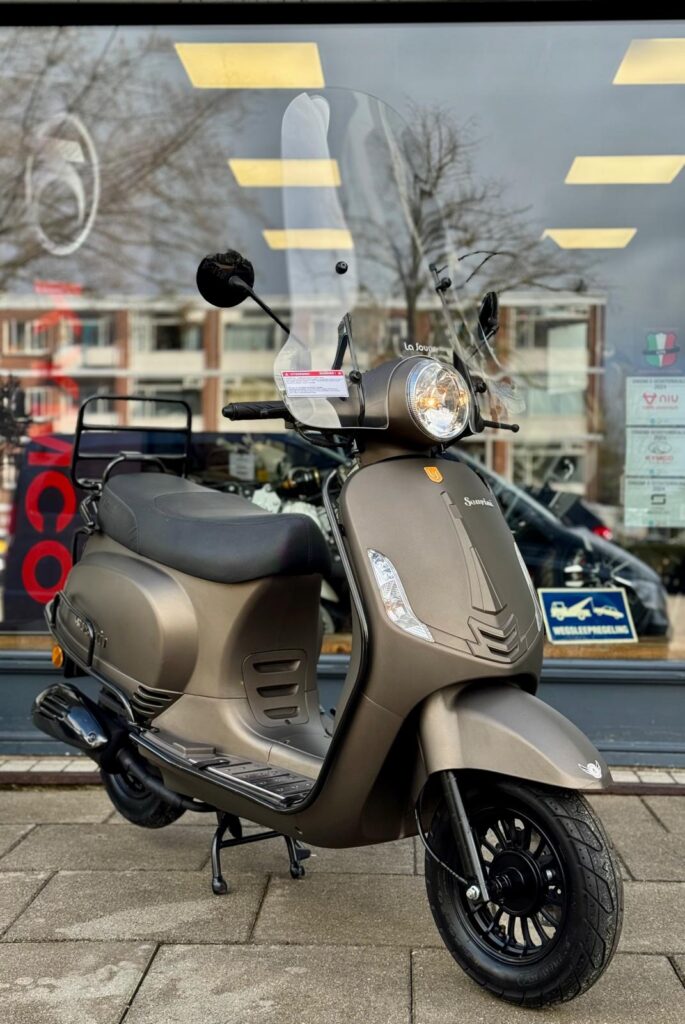 Matbrons retro-scooter met hoog windscherm geparkeerd voor een winkelraam in de stad.