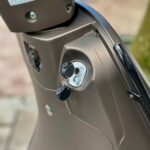 Close-up van een bronskleurige scooter met sleutels in het contactslot.