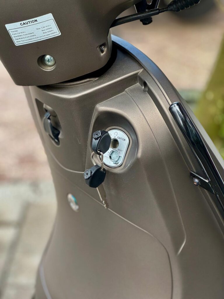 Close-up van een bronskleurige scooter met sleutels in het contactslot.
