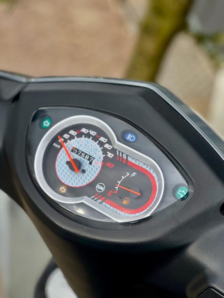 Close-up van het dashboard van een scooter met snelheidsmeter en brandstofmeter.
