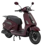 Bordeauxrode retro-scooter met zwart zadel, ronde koplamp en spiegels, schuin van voren gefotografeerd.