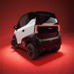 Zwart-witte elektrische microauto, achteraanzicht in studio met rode achtergrond en doorlopende achterlichtbalk.