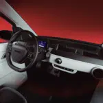 Minimalistisch autointerieur met stuur, digitaal scherm en eenvoudig dashboard tegen rode achtergrond.