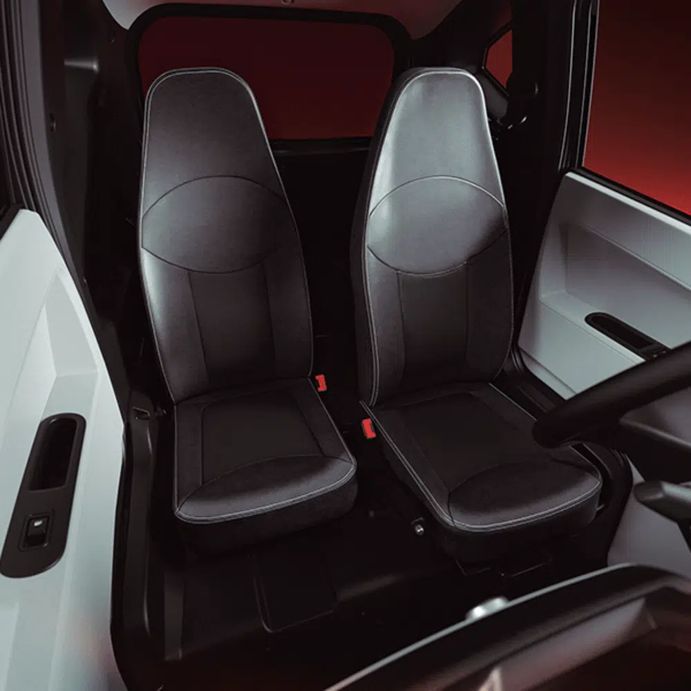 Twee zwarte, smalle autostoelen naast elkaar in een compacte cabine met donker interieur.