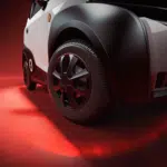 Close-up van het voorwiel en spatbord van een compacte auto op rood verlichte achtergrond.