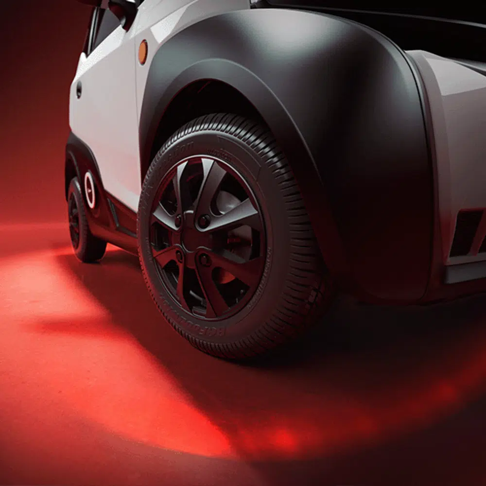 Close-up van het voorwiel en spatbord van een compacte auto op rood verlichte achtergrond.