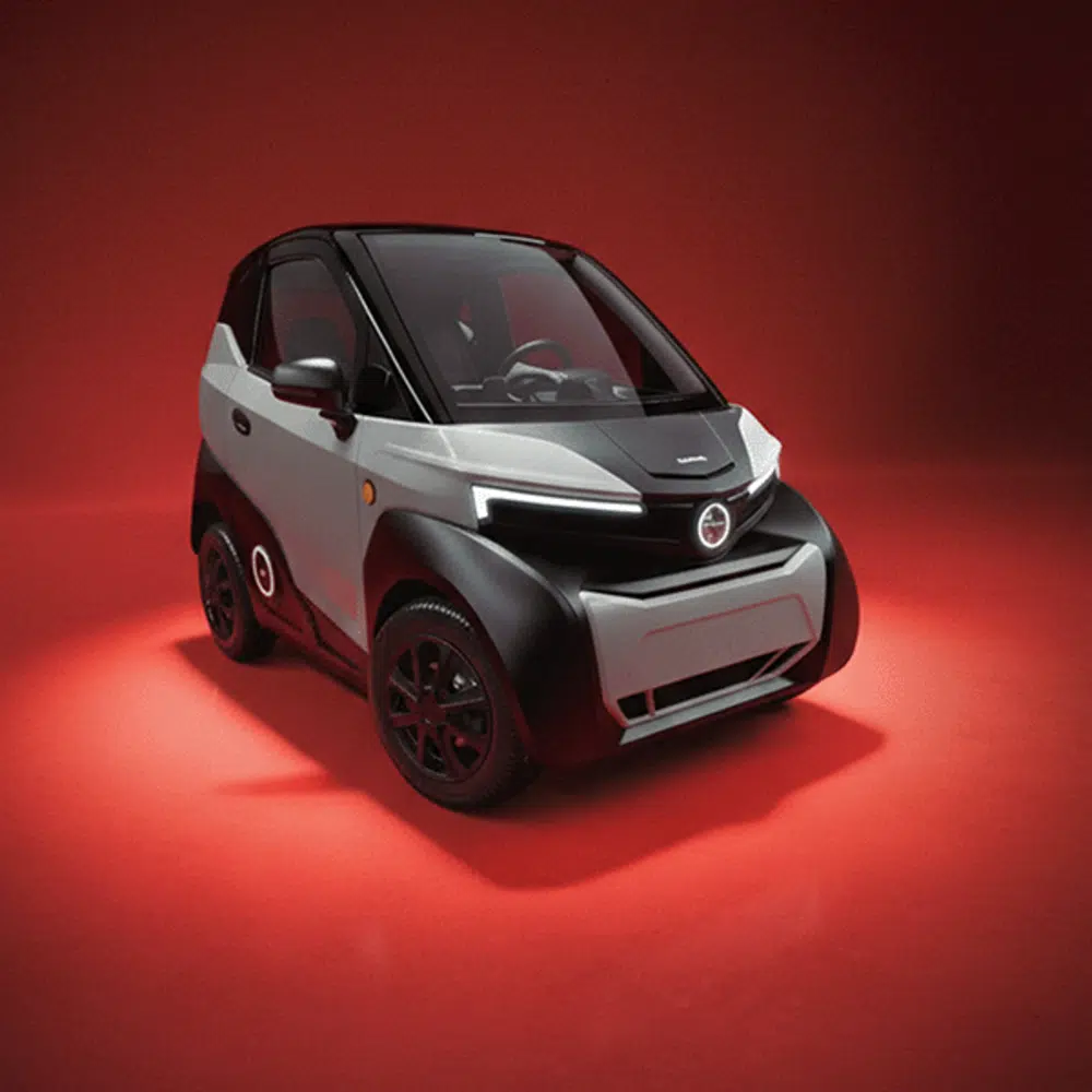 Compacte elektrische microauto in zwart en grijs, gefotografeerd in studio op rode achtergrond.