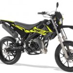 Zwart-gele supermoto bromfiets met hoge spatborden, dikke banden en schijfremmen op witte achtergrond.