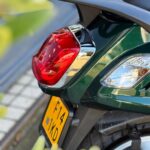 Close-up van de achterzijde van een groene scooter met rood achterlicht en gele kentekenplaat.