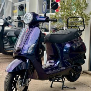 Glanzende paarse scooter met ronde koplamp en bagagerek voor een showroom.