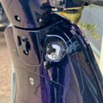 Close-up van een paarse scooter met contactsleutel in het contact en stuurbediening.