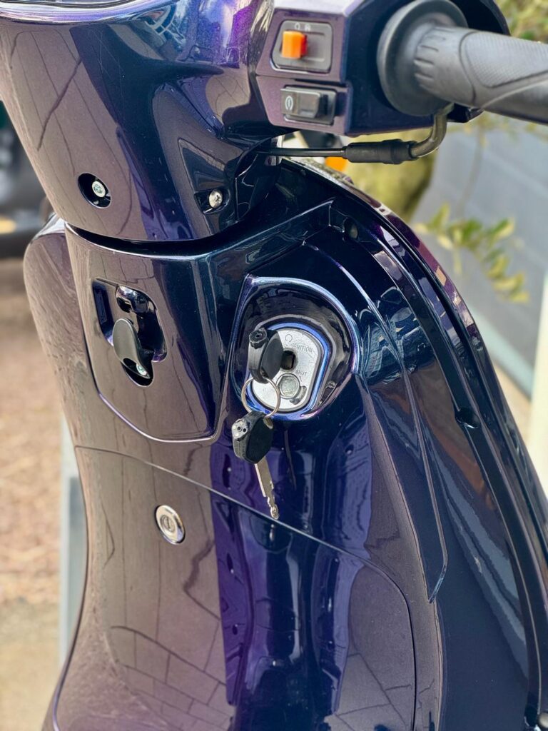 Close-up van een paarse scooter met contactsleutel in het contact en stuurbediening.