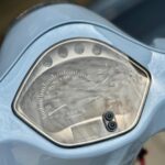 Close-up van de kilometerteller en het dashboard van een lichtblauwe scooter.