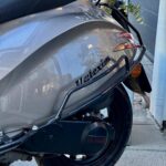 Close-up van de achterzijde van een grijze scooter met Valexim-zadel, achterlicht en achterwiel.