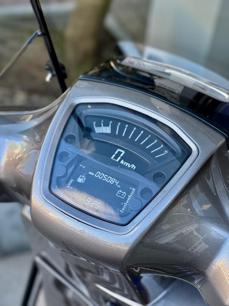 Close-up van het dashboard van een scooter met digitale snelheidsmeter op 0 km/u.