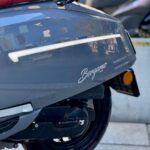 Close-up van de zijkant van een grijze Bergamo-scooter met rood GTS-zadel en zichtbaar achterwiel.